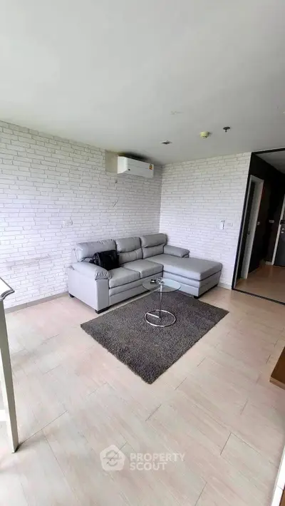 Modern living room with stylish gray sofa and brick accent wall, perfect for relaxation.
