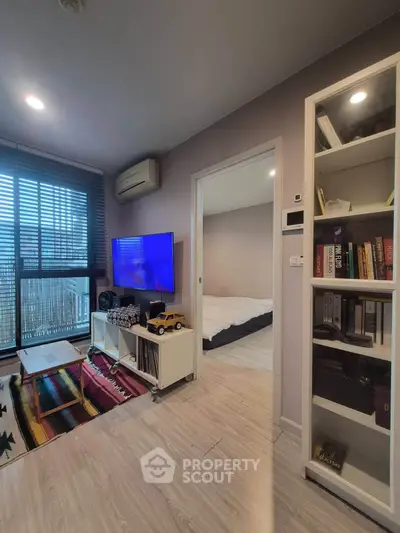 Modern living room with TV, air conditioning, and sliding door to bedroom