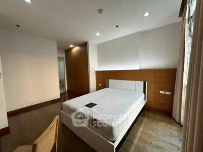 Spacious modern bedroom with wooden flooring and ample natural light.