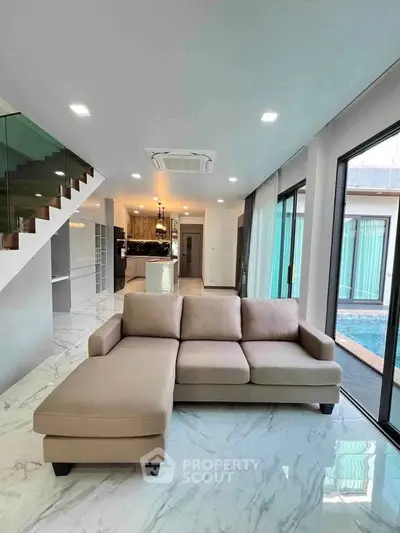 Luxurious modern living room with elegant sofa and pool view, featuring open layout and stylish decor.