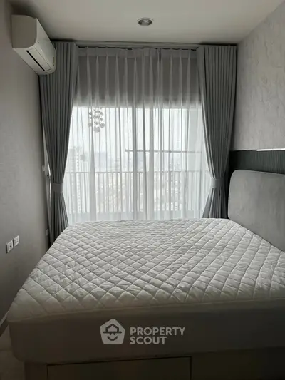 Cozy bedroom with modern decor and large window for natural light.