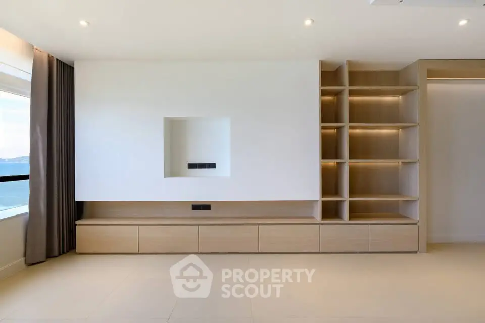 Modern minimalist living room with built-in shelving and large window view.