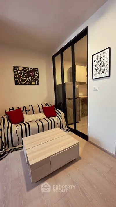 Cozy living room with modern decor and glass partition leading to kitchen