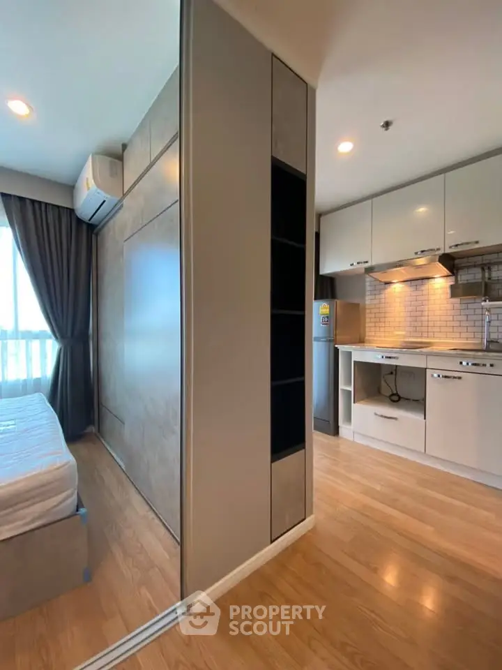 Modern studio apartment with sleek kitchen and cozy bedroom, featuring wooden flooring and ample natural light.