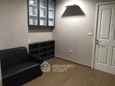 Modern minimalist living room with sleek black sofa and built-in shelving.