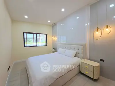 Spacious bedroom with modern lighting and large window for natural light.