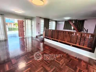 Spacious living room with polished wooden floors and elegant staircase in a modern home.
