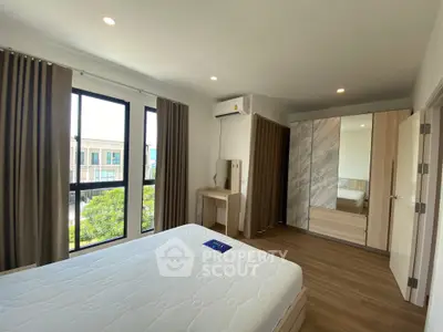 Spacious bedroom with modern furnishings and large windows for natural light.