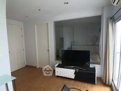Modern living room with sleek TV stand and large window offering natural light.