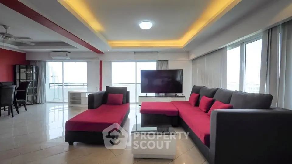 Spacious modern living room with red and black furniture, large windows, and sleek design.