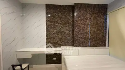 Modern bedroom with elegant marble accent wall and sleek furniture design.