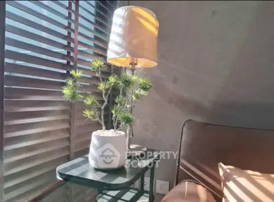 Cozy corner with stylish lamp and plant on side table by window blinds