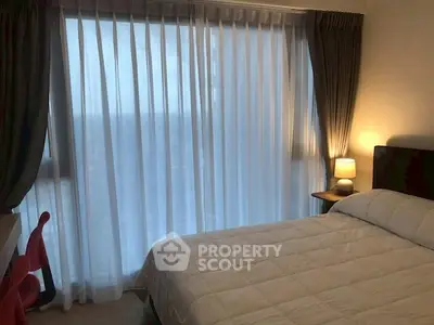 Cozy bedroom with large window and elegant curtains, perfect for relaxation.