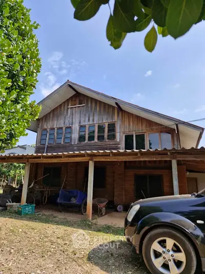 Charming rustic wooden house with spacious front yard and lush greenery.