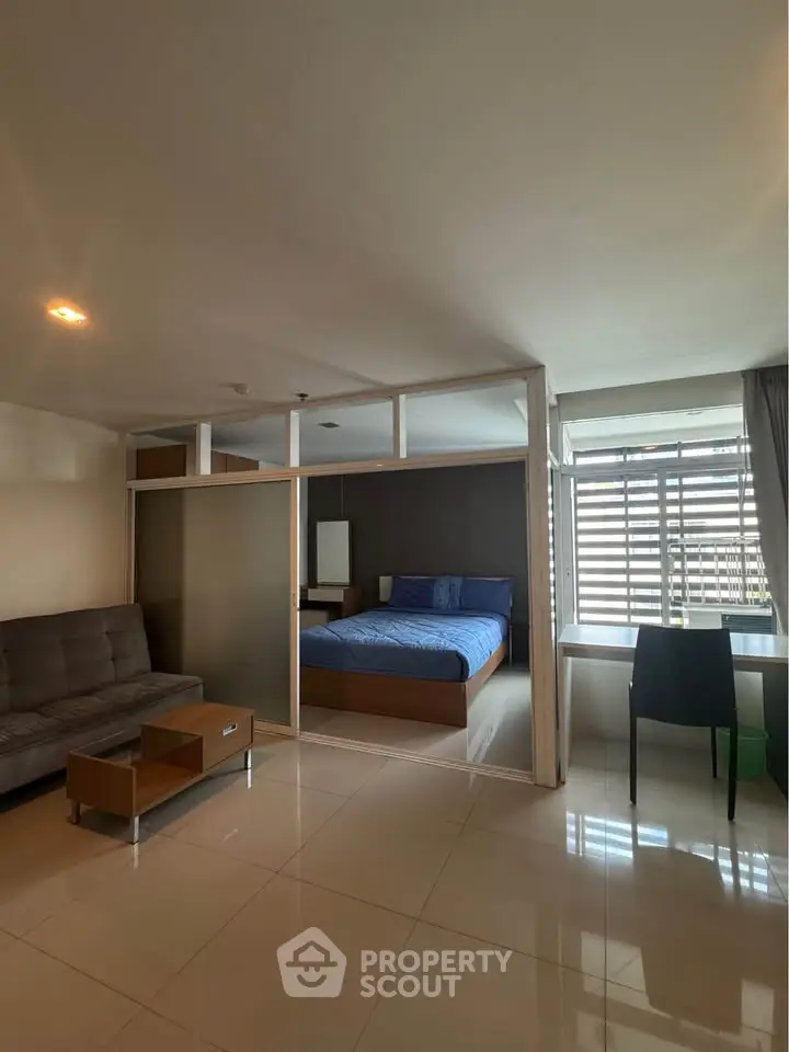 Modern studio apartment with glass partition, cozy living area, and natural light.