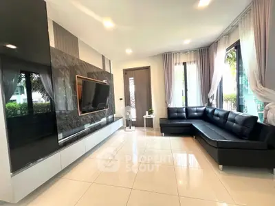 Modern living room with sleek black leather sofa and wall-mounted TV, featuring large windows and elegant decor.