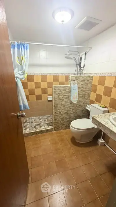 Cozy bathroom with tiled walls and shower area, featuring a modern toilet and sink.