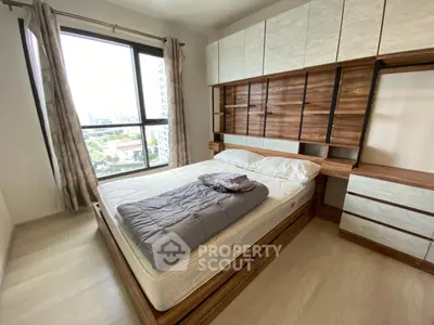 Modern bedroom with large window and stylish wooden furniture in a high-rise apartment.