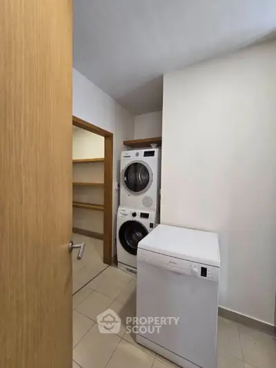 Modern laundry room with stacked washer and dryer, featuring ample shelving space.