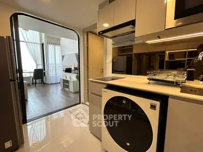 Modern kitchen with sleek appliances and open layout leading to stylish living room.