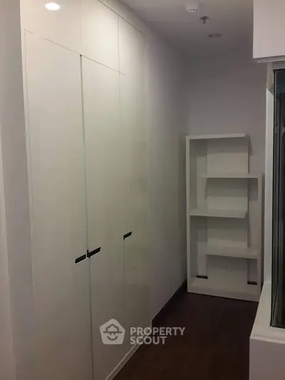 Modern storage space with sleek white cabinets and shelving in a compact room.