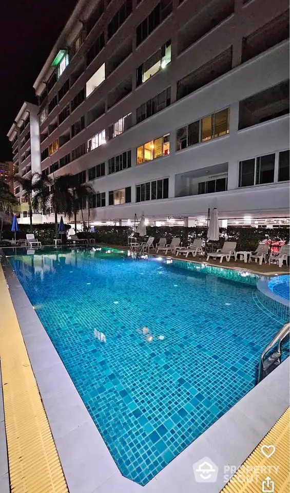 Luxurious apartment building with illuminated poolside at night, perfect for relaxation and leisure.