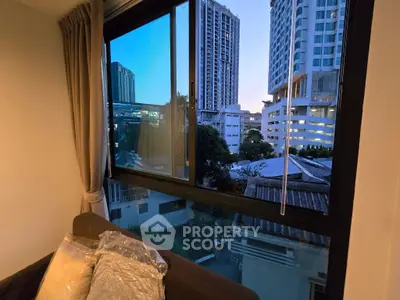 Cozy living room with stunning city view through large window, perfect for urban living.