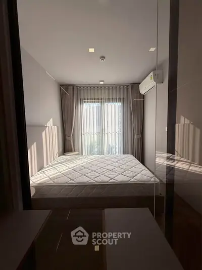 Modern bedroom with large window and natural light, featuring minimalist decor and air conditioning.
