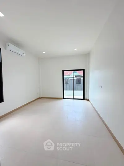 Spacious unfurnished room with large window and air conditioning, perfect for customization.