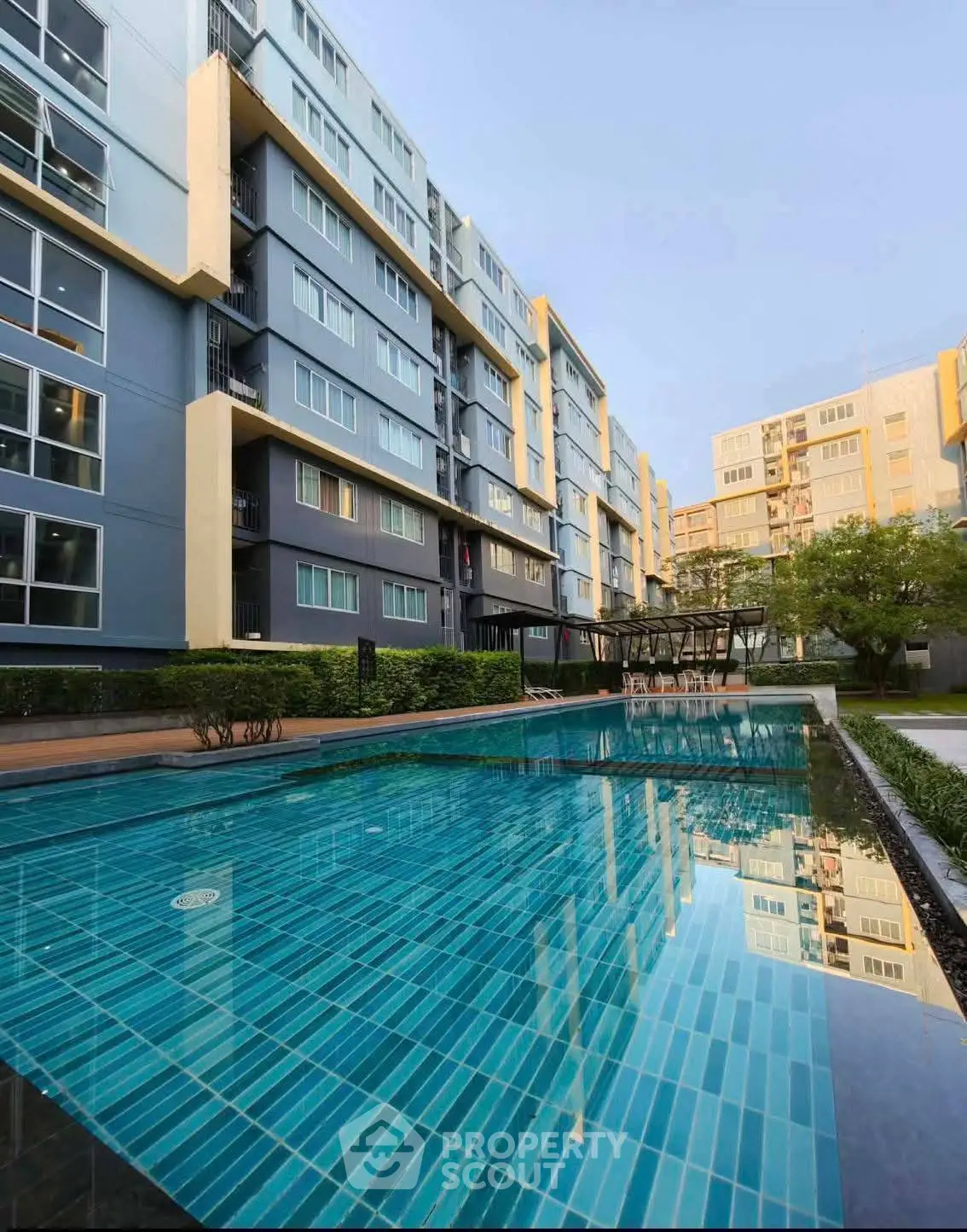 Modern apartment building with a stunning outdoor pool and lush greenery, perfect for urban living.