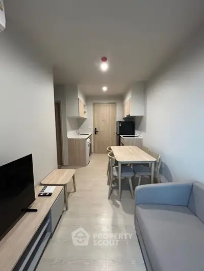 Modern living room with dining area and compact kitchen in open layout apartment.