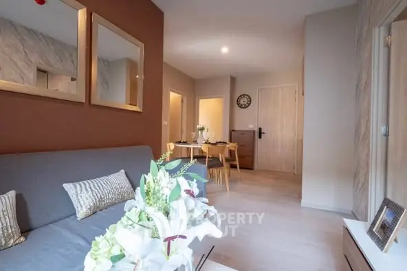 Modern living room with stylish decor and dining area, featuring elegant mirrors and cozy seating.