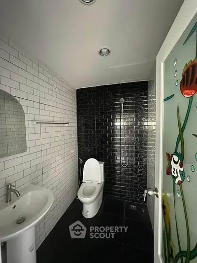 Modern bathroom with sleek black and white tiles and stylish fixtures.