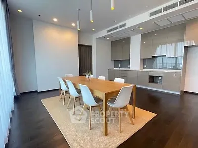 Spacious modern dining area with sleek kitchen in open layout, featuring elegant wooden table and chairs.