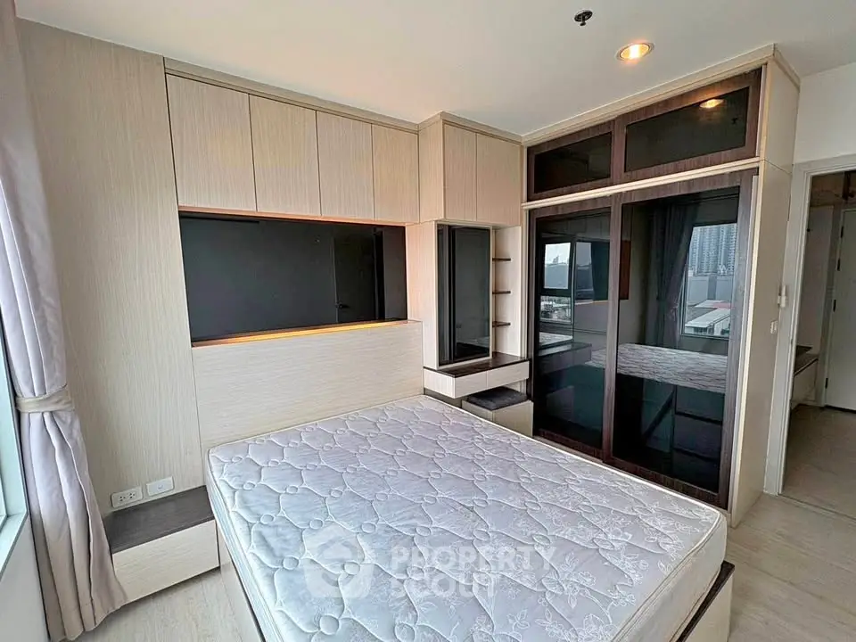 Modern bedroom with built-in storage and large window offering city views.