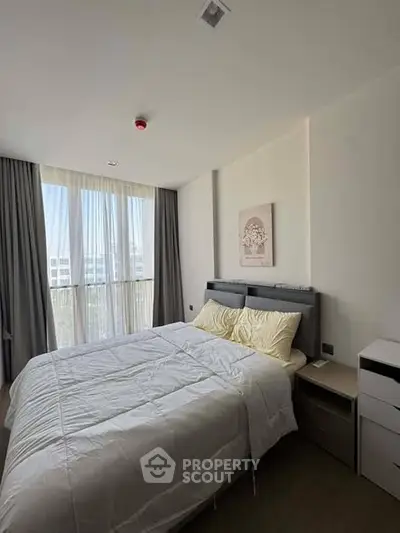 Cozy bedroom with large window and modern decor in a stylish apartment.