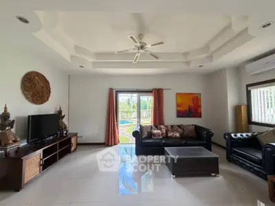 Spacious living room with elegant decor and pool view, featuring modern furniture and ceiling fan.