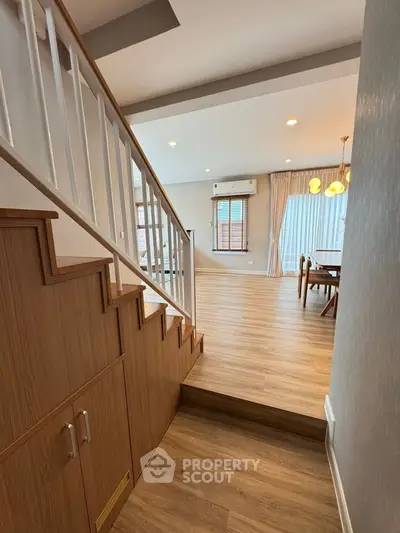 Elegant open-plan living area with wooden flooring and modern staircase