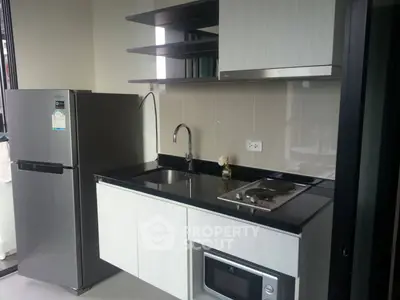 Modern kitchen with sleek cabinetry, stainless steel fridge, and built-in appliances in a compact layout.