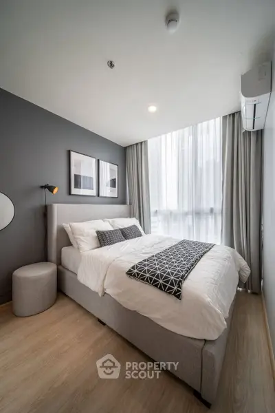 Modern bedroom with stylish decor and large window for natural light.