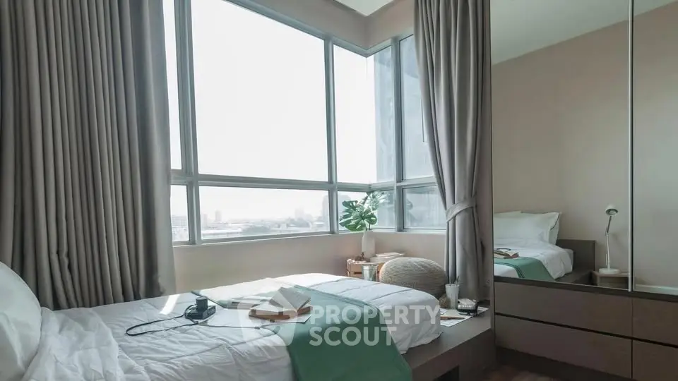 Cozy bedroom with large windows offering city views, featuring a comfortable bed and modern decor.