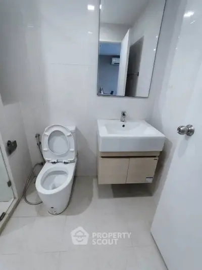 Modern bathroom with sleek fixtures and minimalist design, featuring a wall-mounted sink and toilet.