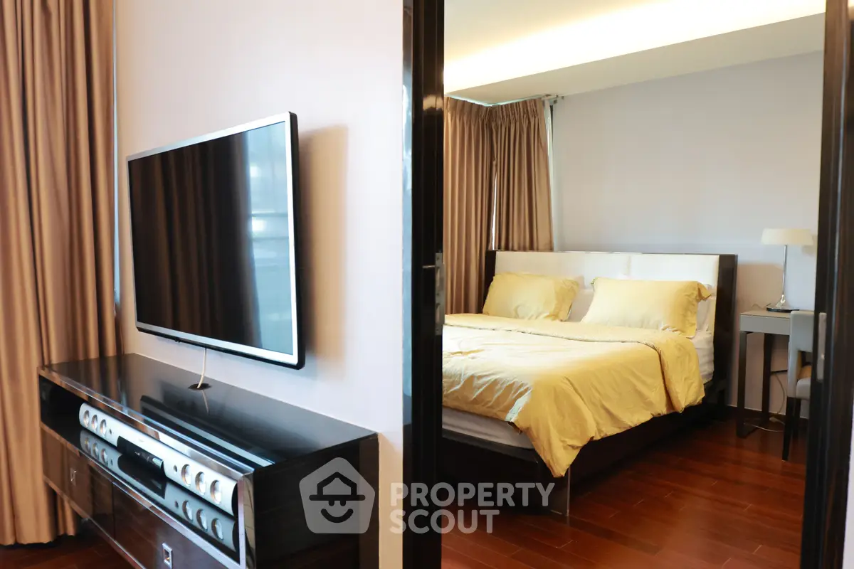 Modern bedroom with sleek TV setup and elegant wooden flooring