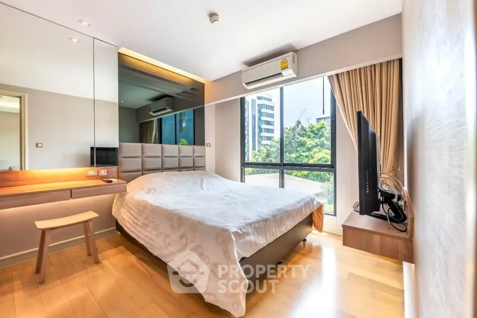 Modern bedroom with large window and city view, featuring stylish decor and natural light.