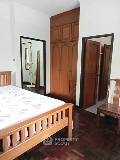 Spacious bedroom with wooden furniture and built-in wardrobe, perfect for cozy living.