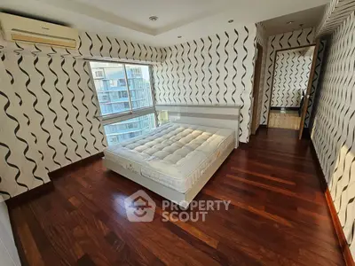 Spacious bedroom with modern design and large window offering city views, featuring elegant wooden flooring.