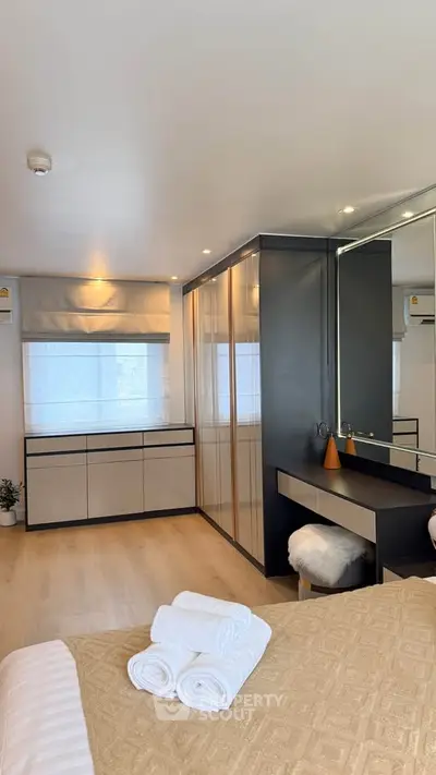 Luxurious bedroom with modern decor and ample natural light, featuring a stylish vanity and cozy ambiance.