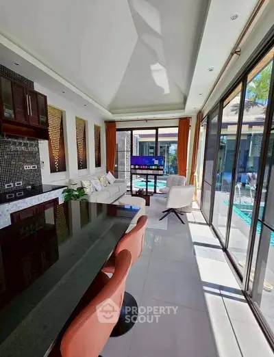 Luxurious living room with modern decor and pool view, featuring open layout and elegant furnishings.