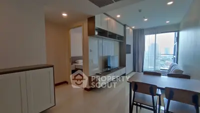 Modern apartment interior with open living and dining area, featuring sleek furniture and city view.