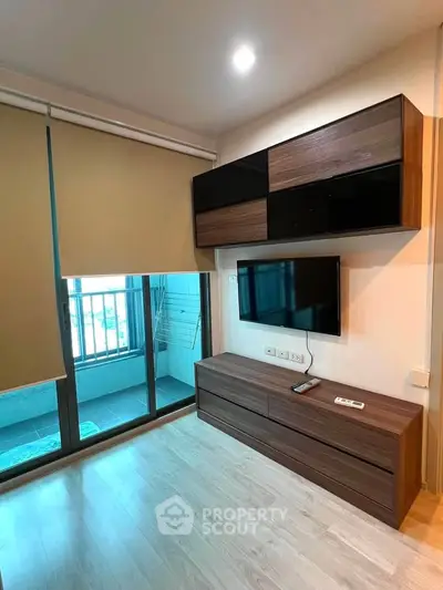 Modern living room with sleek TV unit and balcony access, featuring stylish wood flooring and contemporary design.